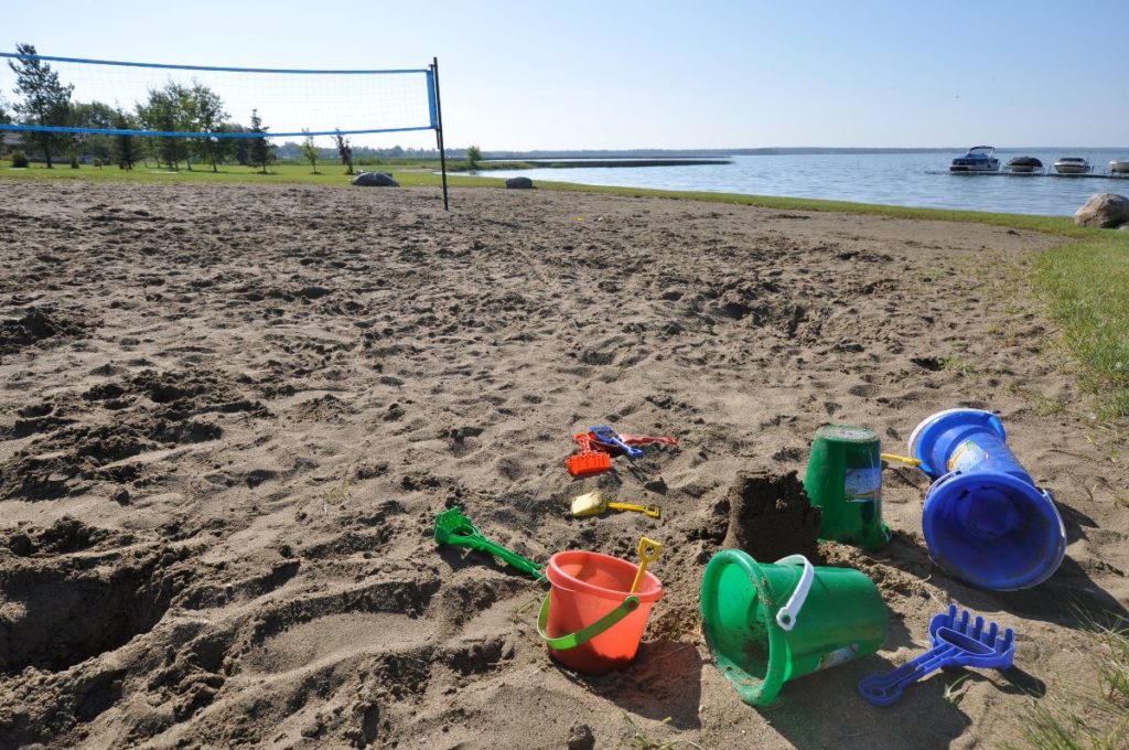 Sand toys on a beach with a beach volleyball net in the background