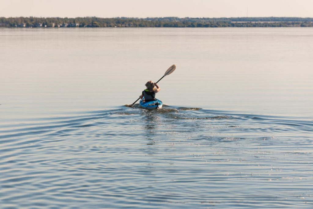 A single person is kayaking on a pristine lake